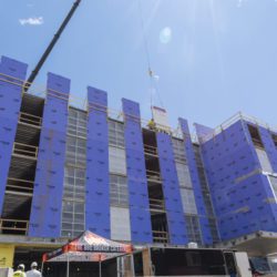 Looking up at a construction crane setting the final piece of steel structure in place on the Cambria Hotel Somerville-Cambridge