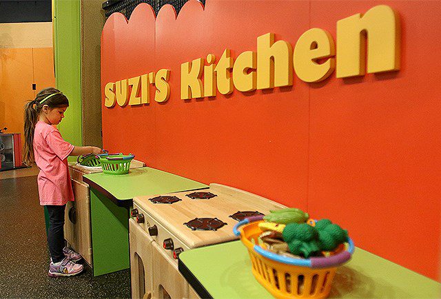 A young girl plays with a toy kitchen in he OH WOW Children's Center