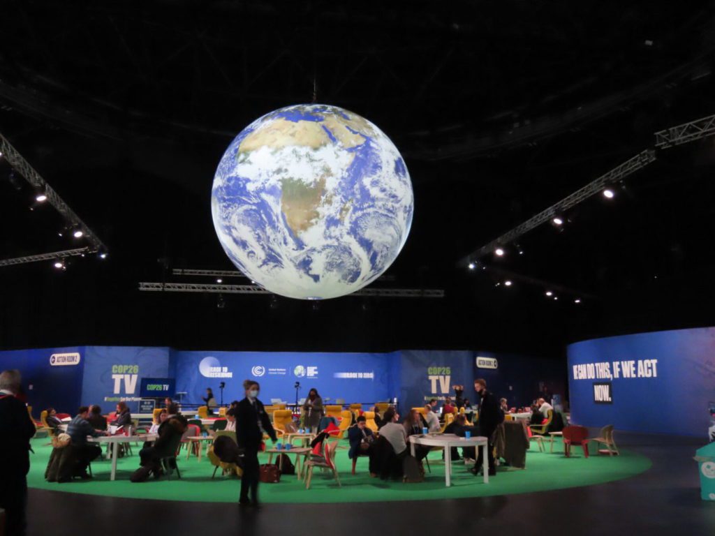 A large globe floats above the conference space at COP26