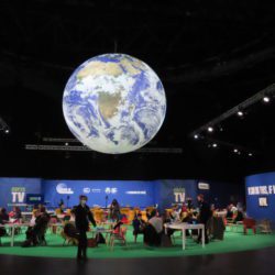 A large globe floats above the conference space at COP26