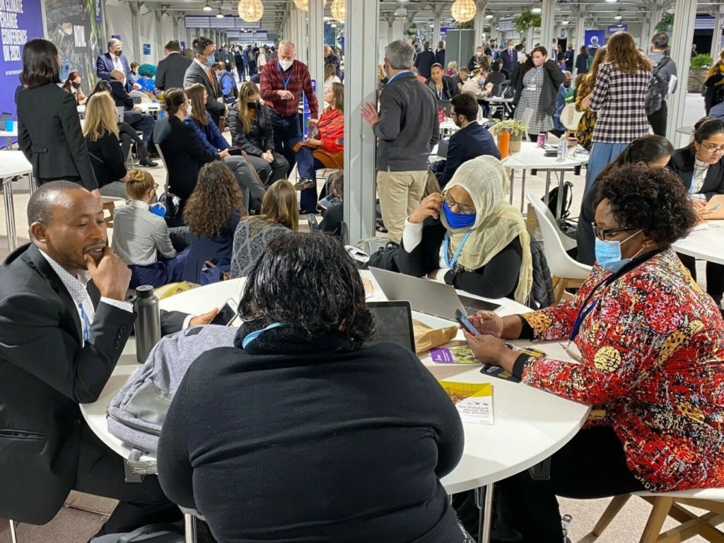 People gather at tables for discussions at COP26