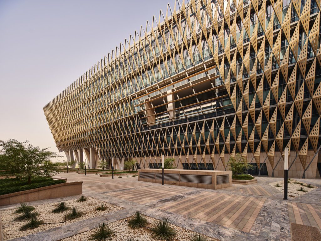 Side view of a building with diamond shaped gold metal panels in the desert
