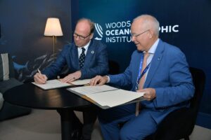 Peter de Menocal and François Houllier sign documentation that extends their working partnership in exploration, study, and protection of the world’s oceans in a breakout space at the Ocean Pavilion