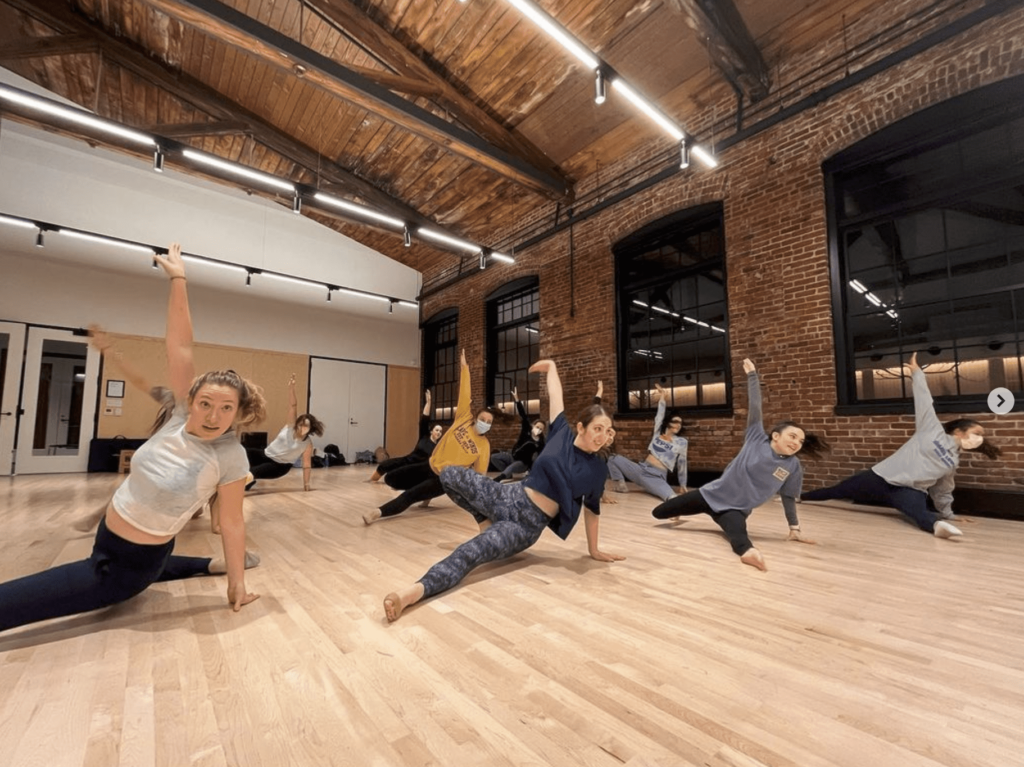 A dance troupe practices at a public studio space.